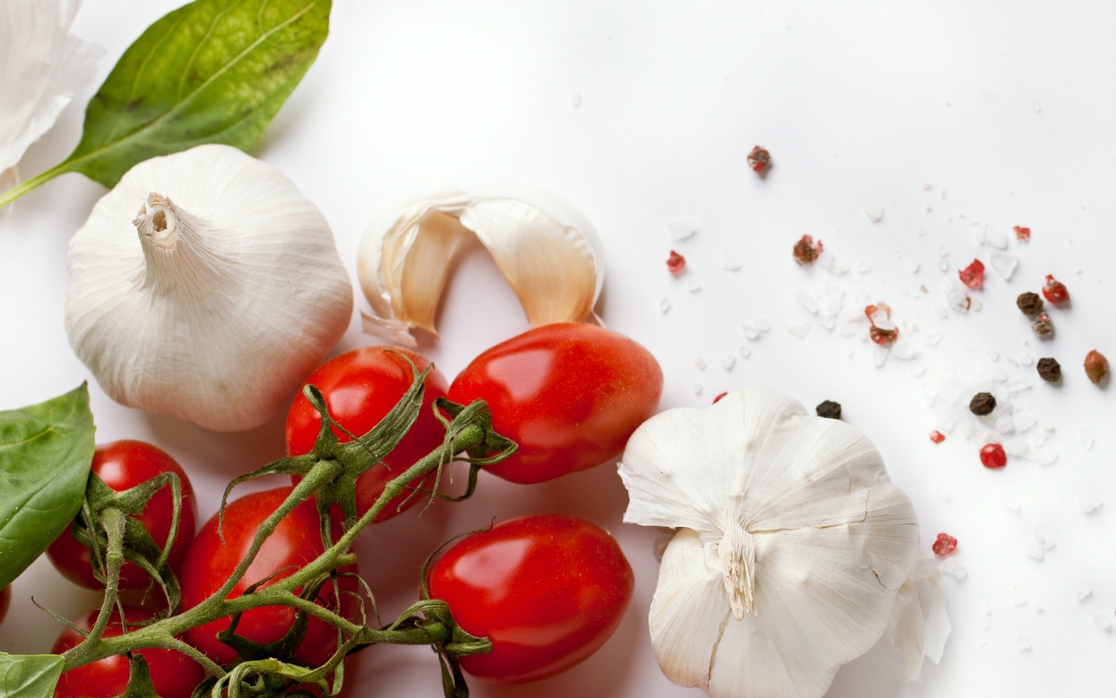 Tomaten, knoblauch und basilikum auf einer weißen fläche mit pfeffer (knoblauch, essen, naturkost, gemüse, frucht)