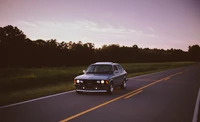 BMW E9 classique sur une route ouverte au crépuscule