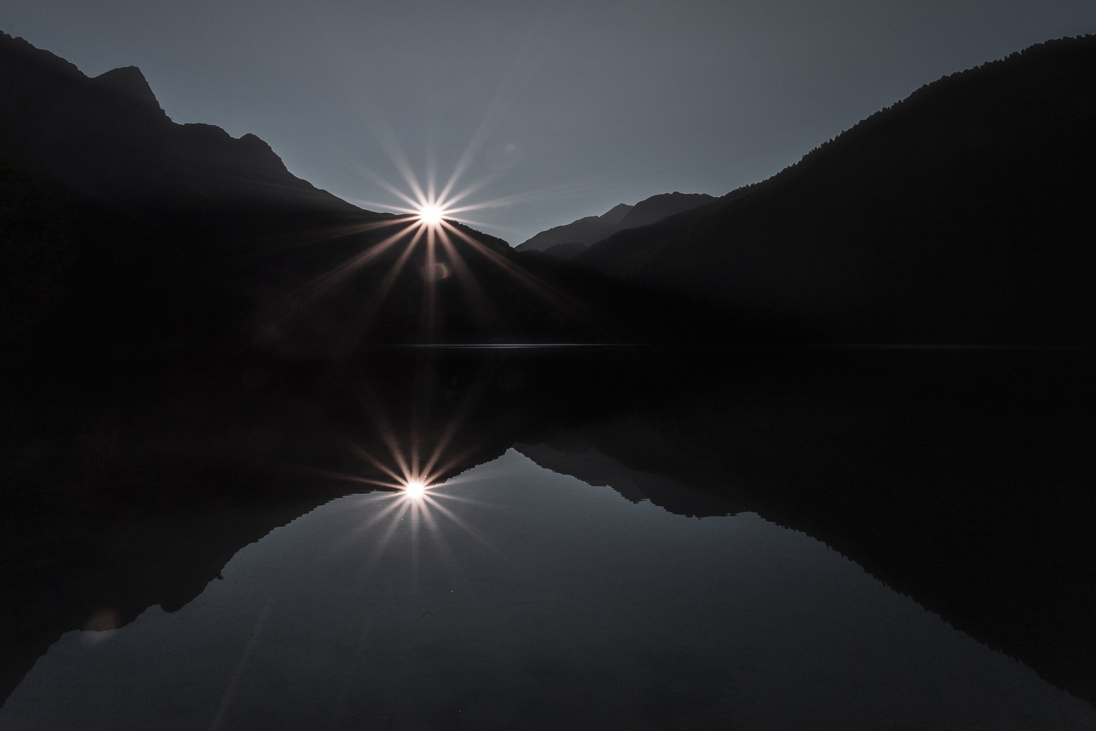 Une vue arabe d'une chaîne de montagnes avec un lac et le soleil (lumière, éclat de lentille, eau, béatitude, nature)