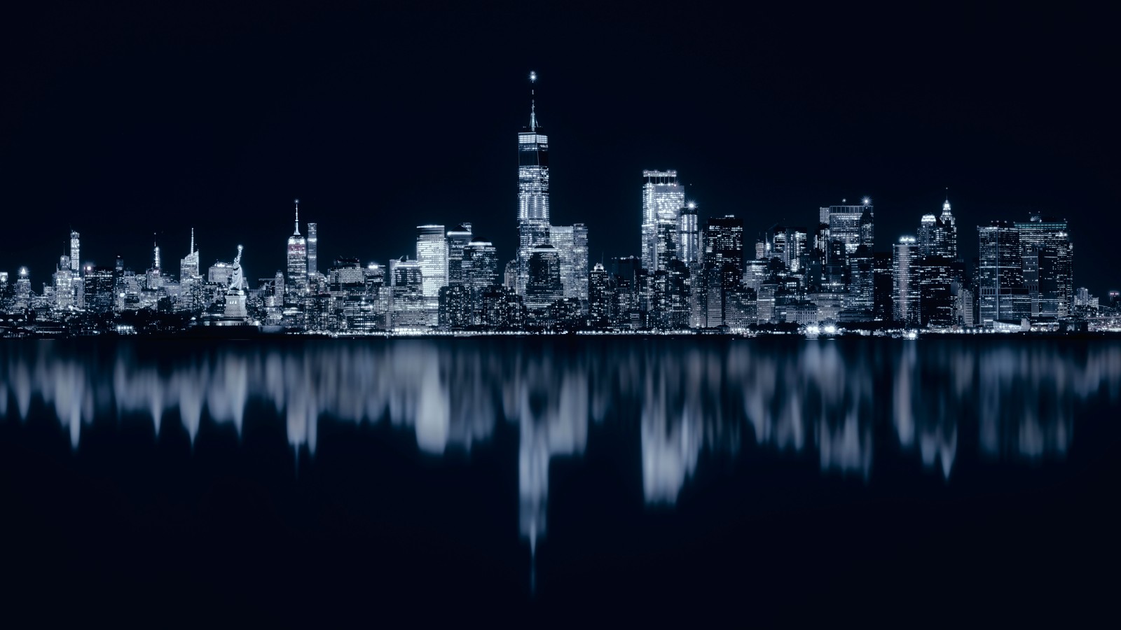 A black and white photo of a city skyline at night (new york city, night, cityscape, city lights, reflections)