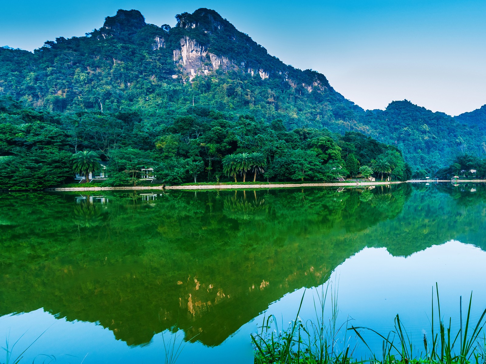 Montañas reflejadas en un lago con un cielo azul (vietnam, montaña, reserva natural, naturaleza, reflexión)