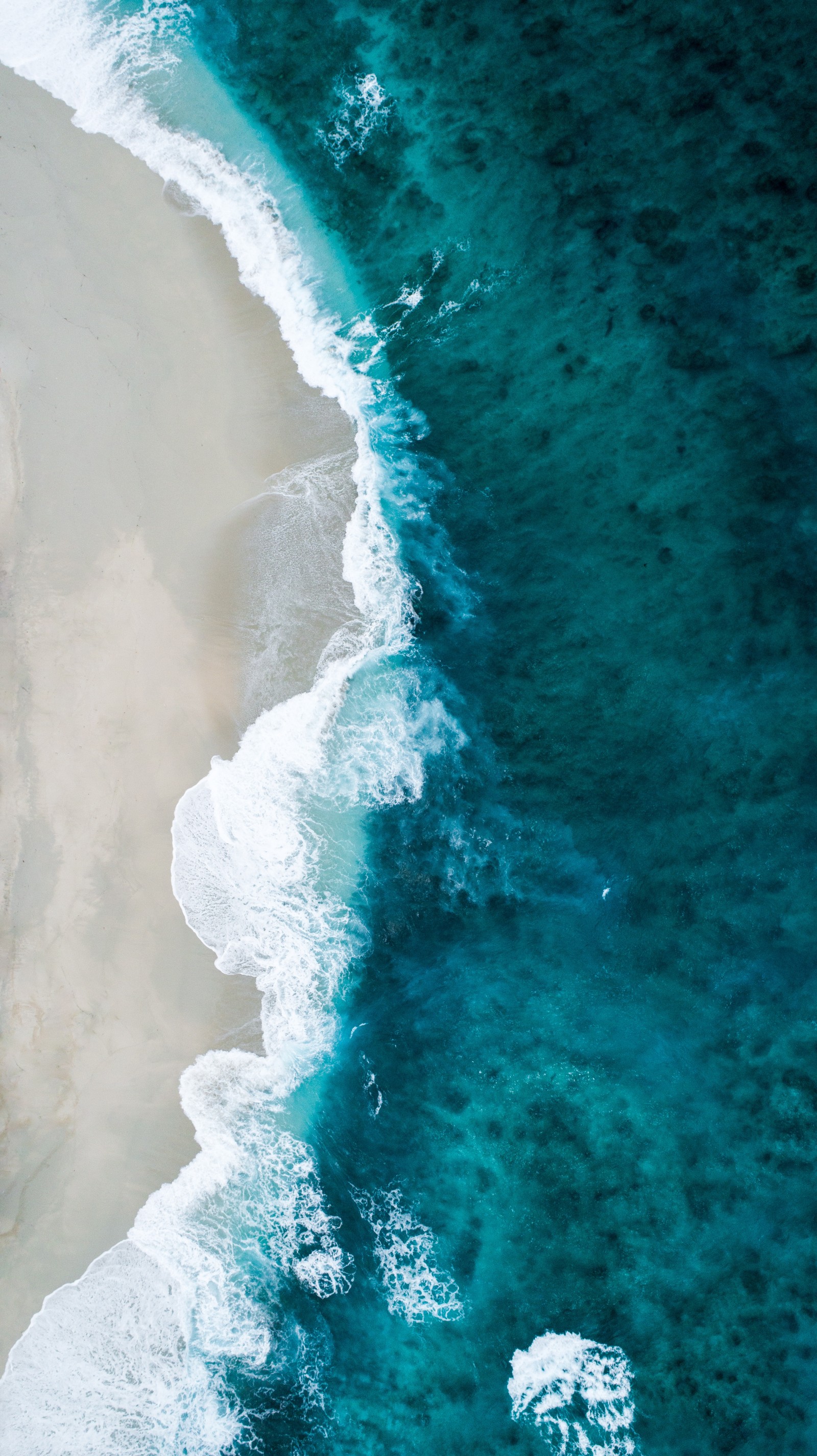 Vue aérienne d'une plage avec une planche de surf et un plan d'eau (océan, eau, mer)