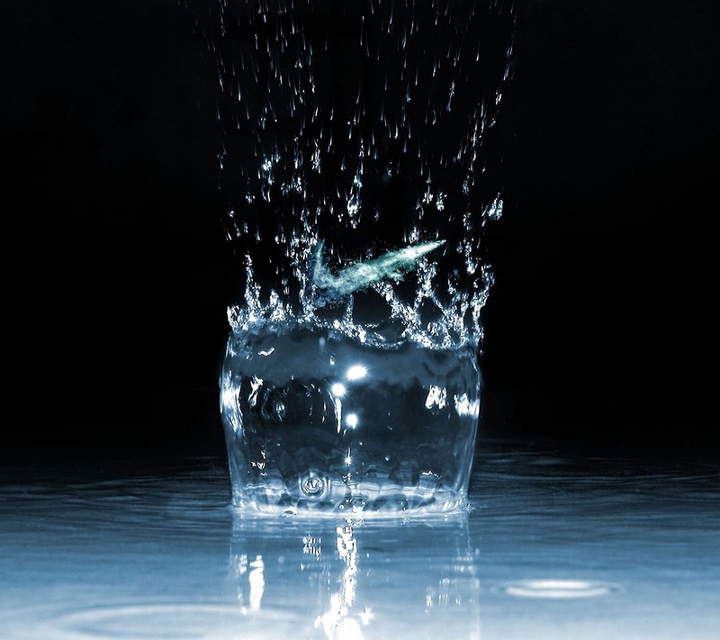 Un verre d'eau avec une brosse à dents verte dedans (logo, nike)