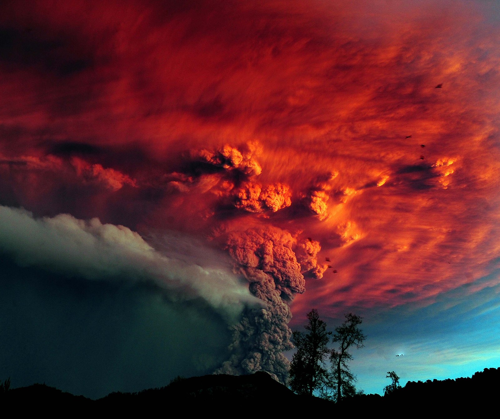 A red cloud is seen in the sky above a volcano (abstract, sky)