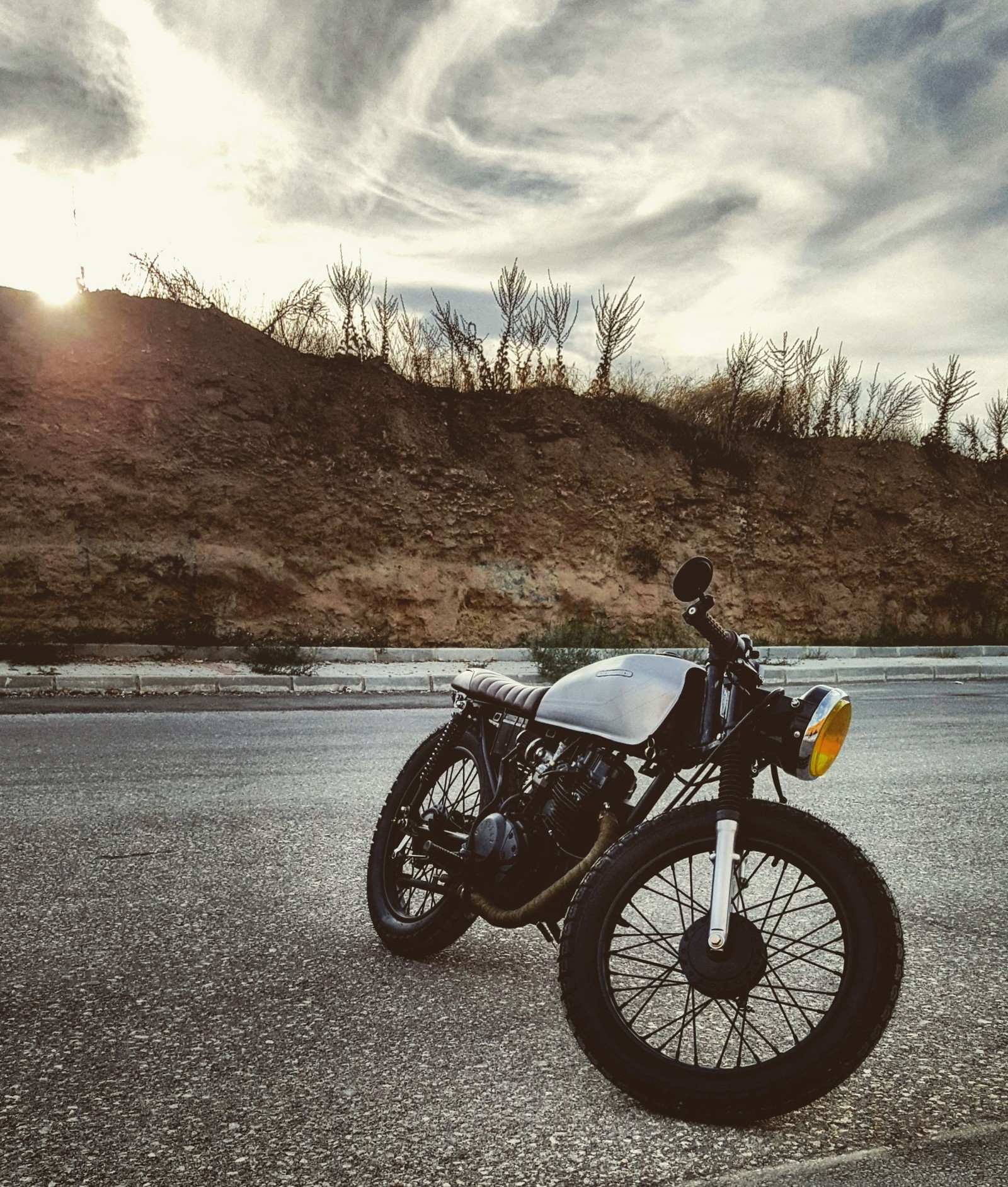 Hay una motocicleta estacionada al lado de la carretera (cafe racer, motocicleta)