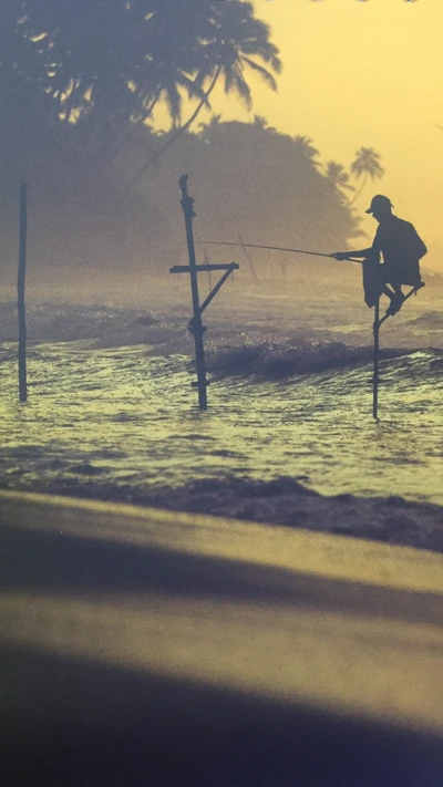 Silhueta de um pescador em pé em um suporte no oceano durante o nascer do sol.