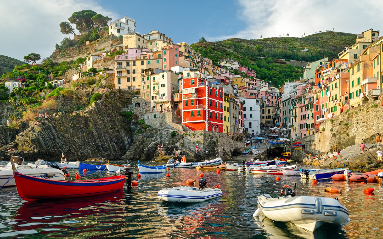 Barcos estão atracados na água perto de uma pequena cidade (riomaggiore, costa, transporte aquático, água, cidade)