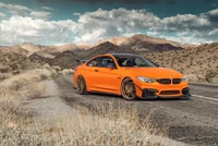 Vibrante BMW M3 naranja en una carretera desértica contra un fondo montañoso