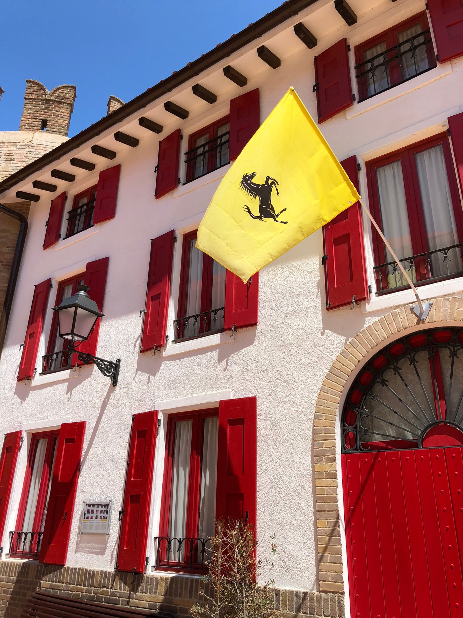 Una bandera amarilla ondeando frente a un edificio (bienes raíces, propiedad, rojo, fachada, bandera)