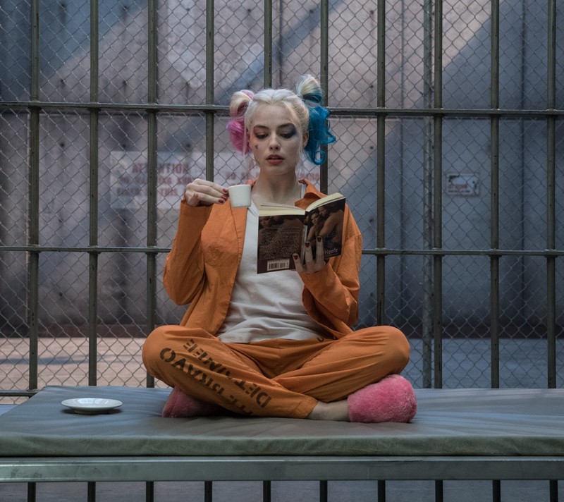 Жираф, сидящий на скамейке и читающий книгу в тюремной камере (синий, harley quinn, монстр, оранжевый, красный)