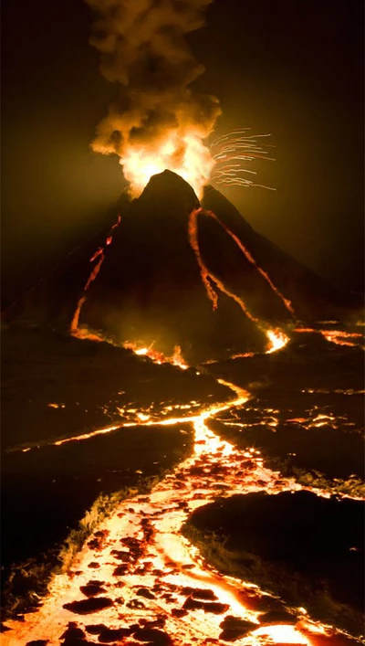 Éruption volcanique la nuit : flammes et lave illuminant le ciel