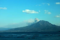 Stratovolcan serein surplombant des eaux océaniques calmes et des nuages cumulus