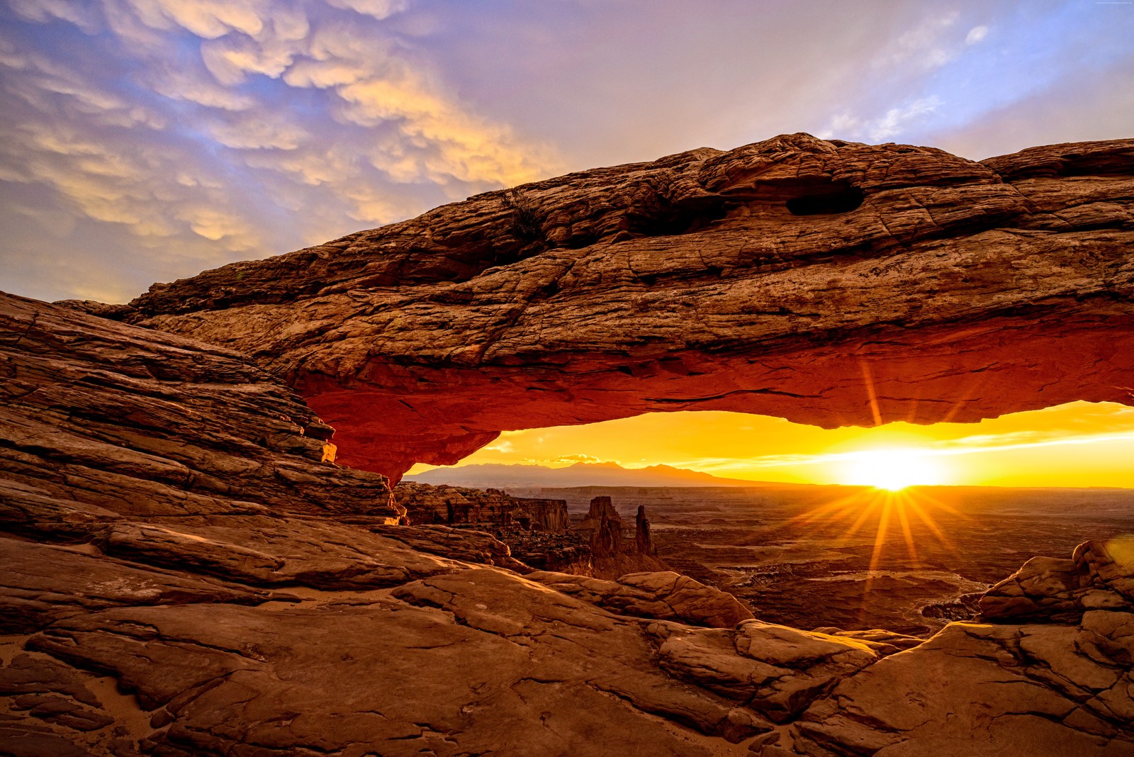 A close up of a rock formation with a sun setting in the background (8k, desert, sunset)