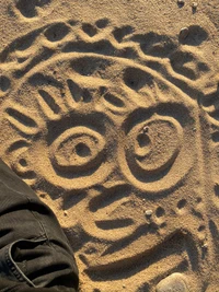 Intricate Sand Carving: A Playful Face in Beige Patterns