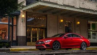 Um elegante Mercedes-Benz CLS vermelho estacionado em frente a um edifício clássico, exibindo seu design esportivo e presença luxuosa.