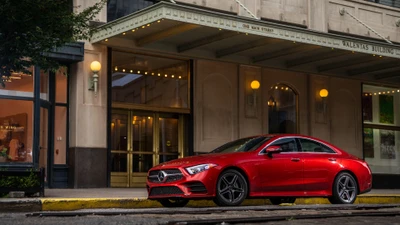 Un elegante Mercedes-Benz CLS rojo estacionado frente a un edificio clásico, mostrando su diseño deportivo y presencia lujosa.