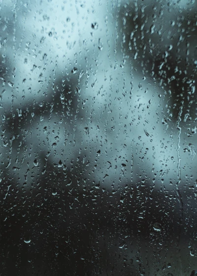 Gouttes de pluie sur une surface en verre contre un fond d'humeur bleue.