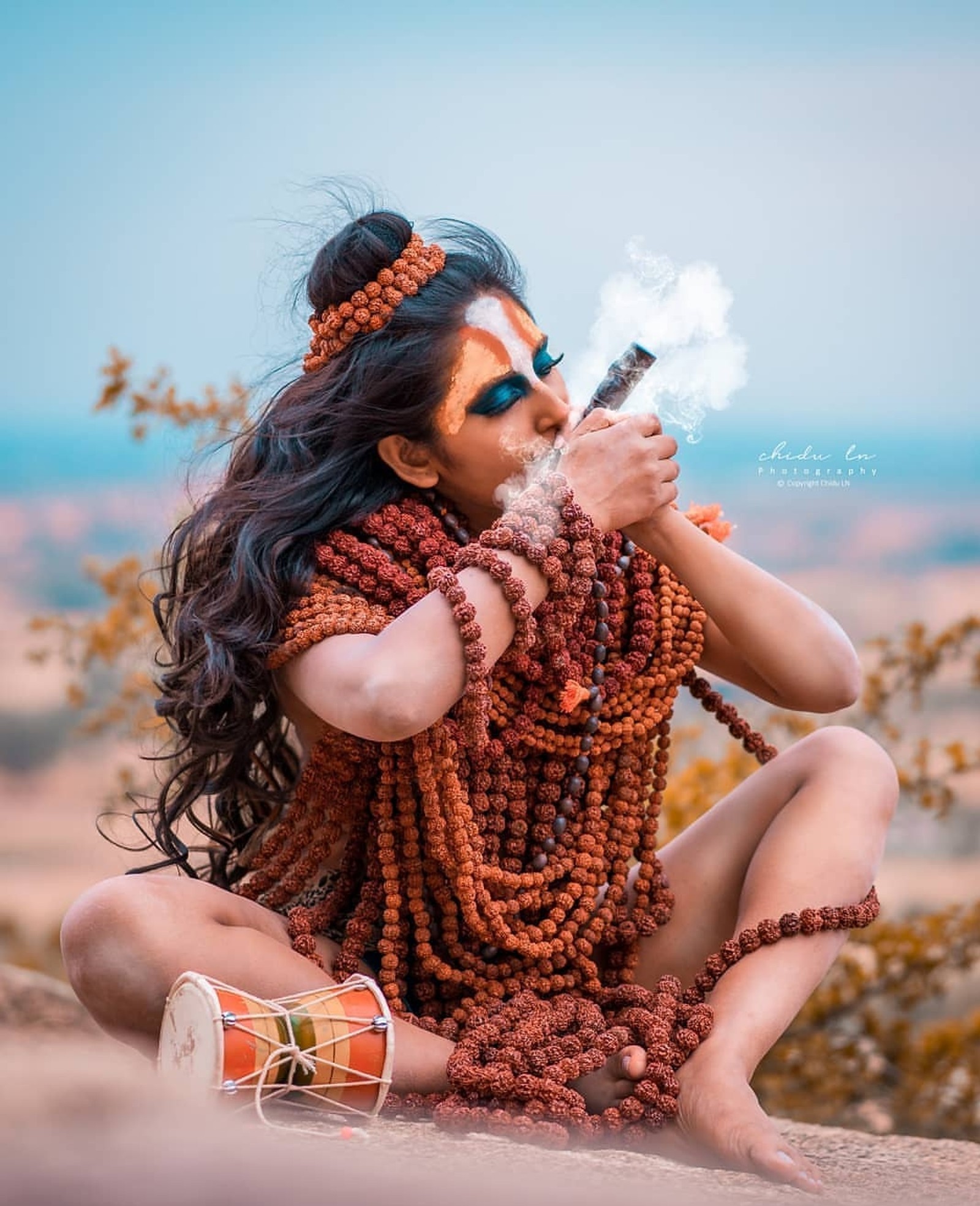 Arafed woman with a cigarette and a necklace smoking a cigarette (baba bhole, love)