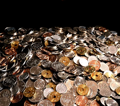 A pile of assorted coins reflecting light, showcasing various denominations and colors.