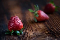 Frische, reife Erdbeeren auf einer rustikalen Holzoberfläche, die ihre lebendige rote Farbe und natürliche Süße hervorheben.