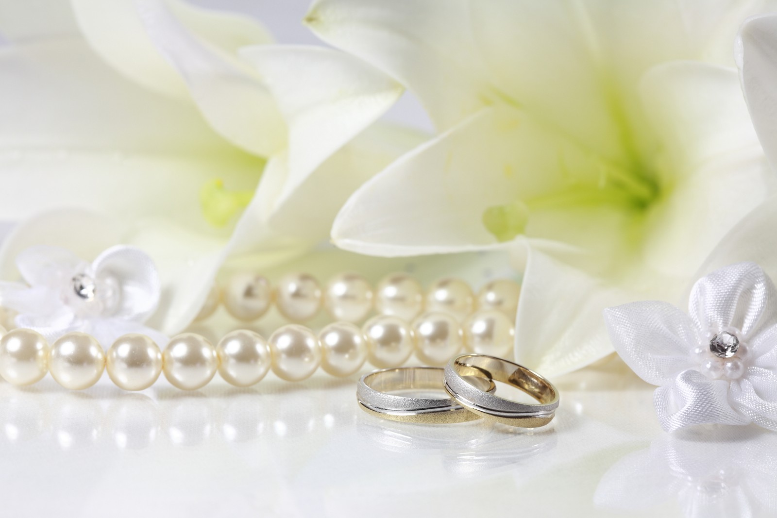 Hay dos anillos de bodas y un collar de perlas sobre una mesa (invitación de boda, boda, anillo de bodas, blanco, perla)