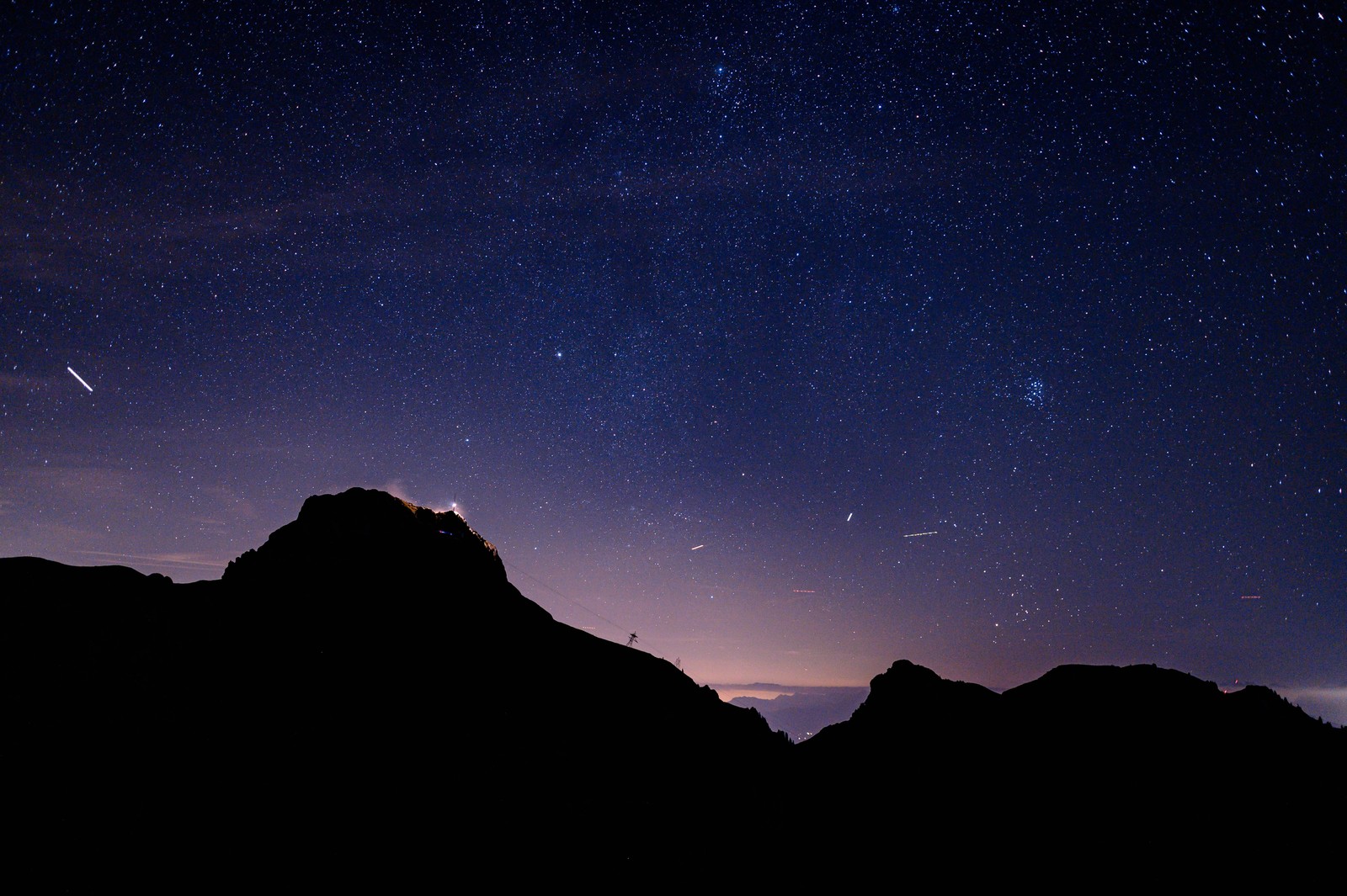 Uma vista do céu noturno com estrelas e uma estrela cadente (noite, montanha, preto, azul, formas montanhosas)