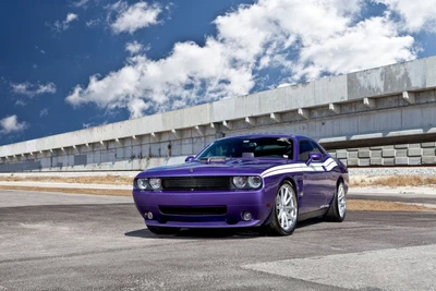 Dodge Challenger Hellcat violet avec des jantes élégantes garé sur une route déserte sous un ciel bleu.