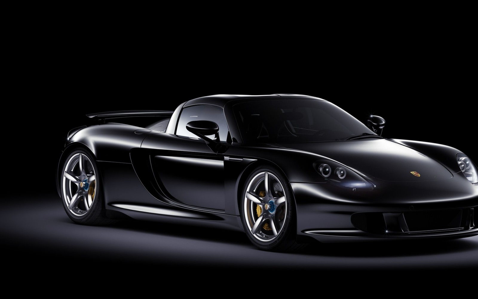 Um close de um carro esportivo preto em uma sala escura. (carro esportivo, porsche, porsche 911, supercarro, porsche carrera gt)