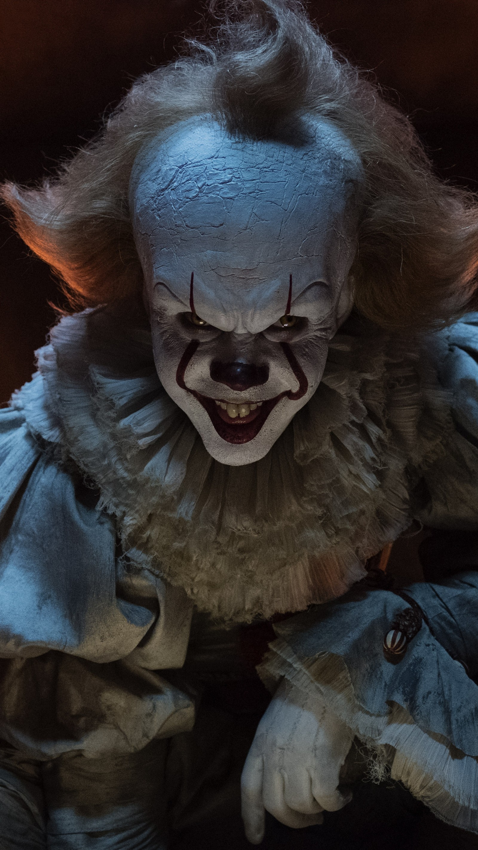 Um palhaço com rosto branco, nariz vermelho e dentes brancos em um quarto escuro (it, pennywise)