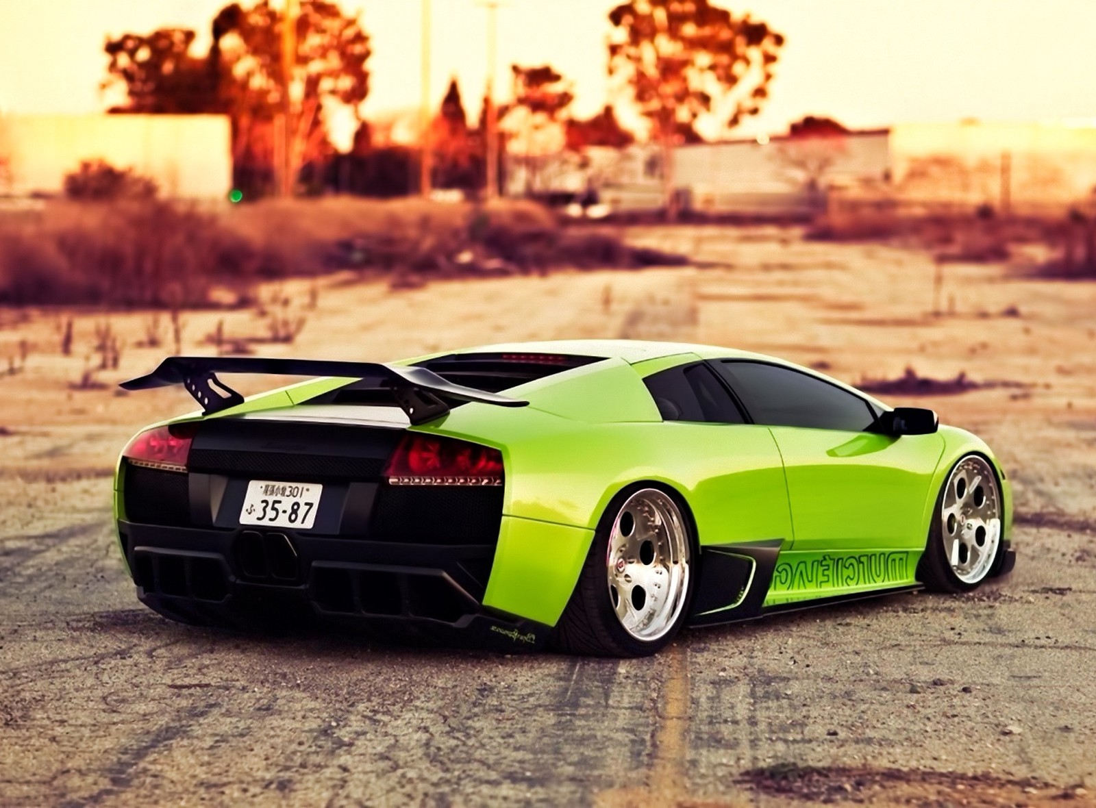 A close up of a green sports car parked on a dirt road (auto, green, lamborghini, sunset, wild)