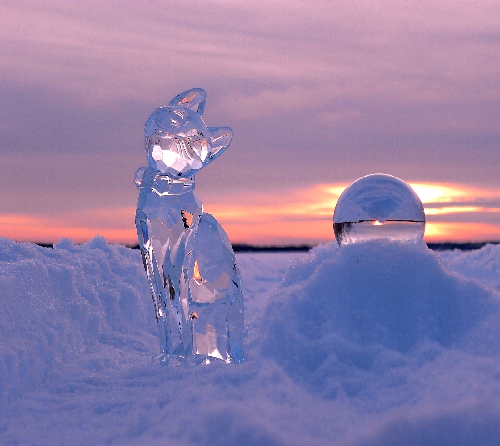 Hay una estatua de gato de vidrio sentada en la nieve (cat)