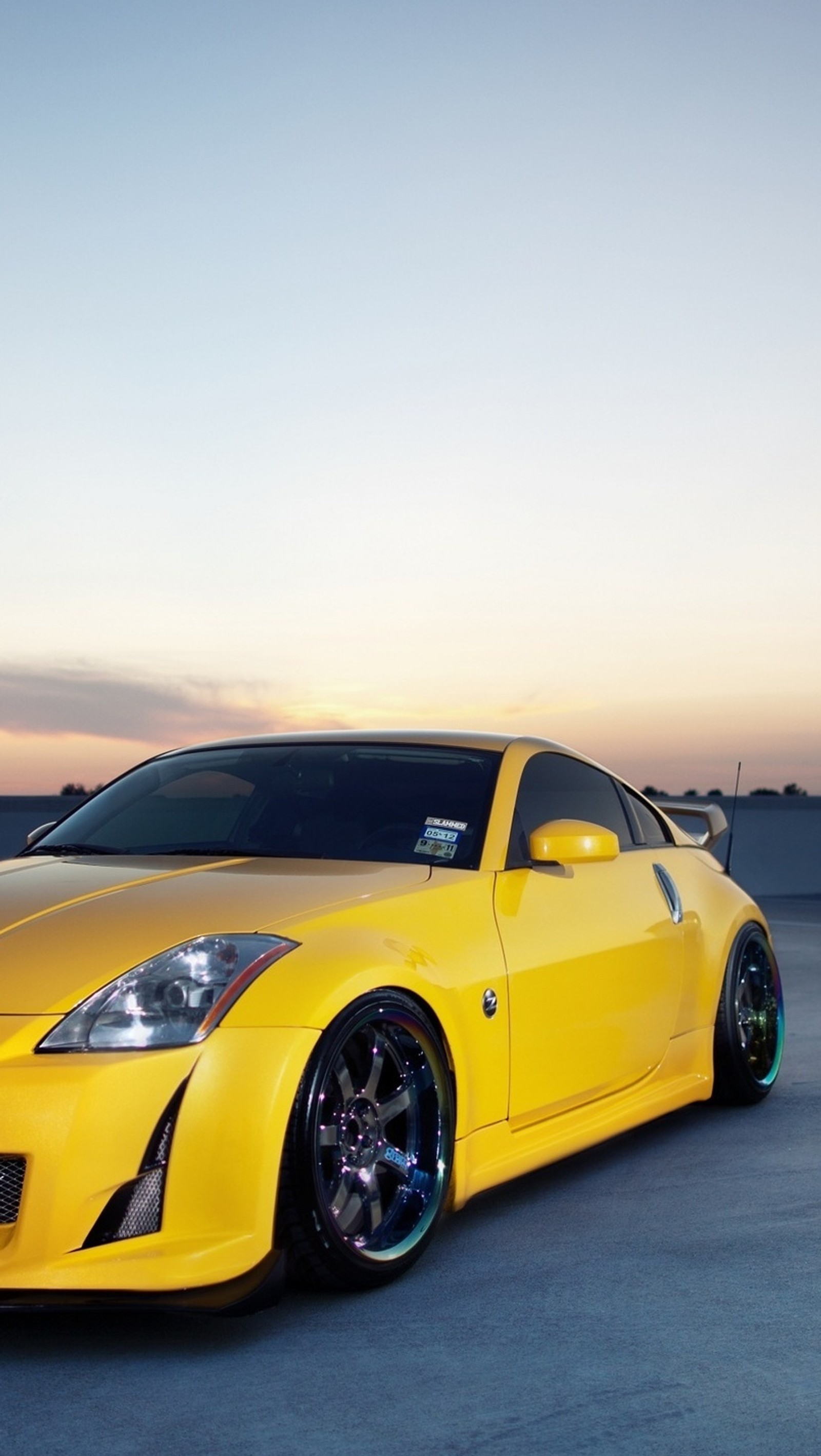 Yellow sports car parked on concrete with sunset in background (350z, black, car, fast, nissan)