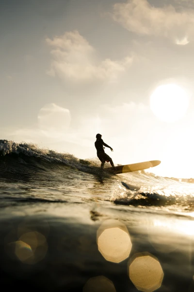 Silhouette eines Surfers, der bei Sonnenuntergang auf einer Welle reitet und das Wesen von Wassersport und Freiheit einfängt.