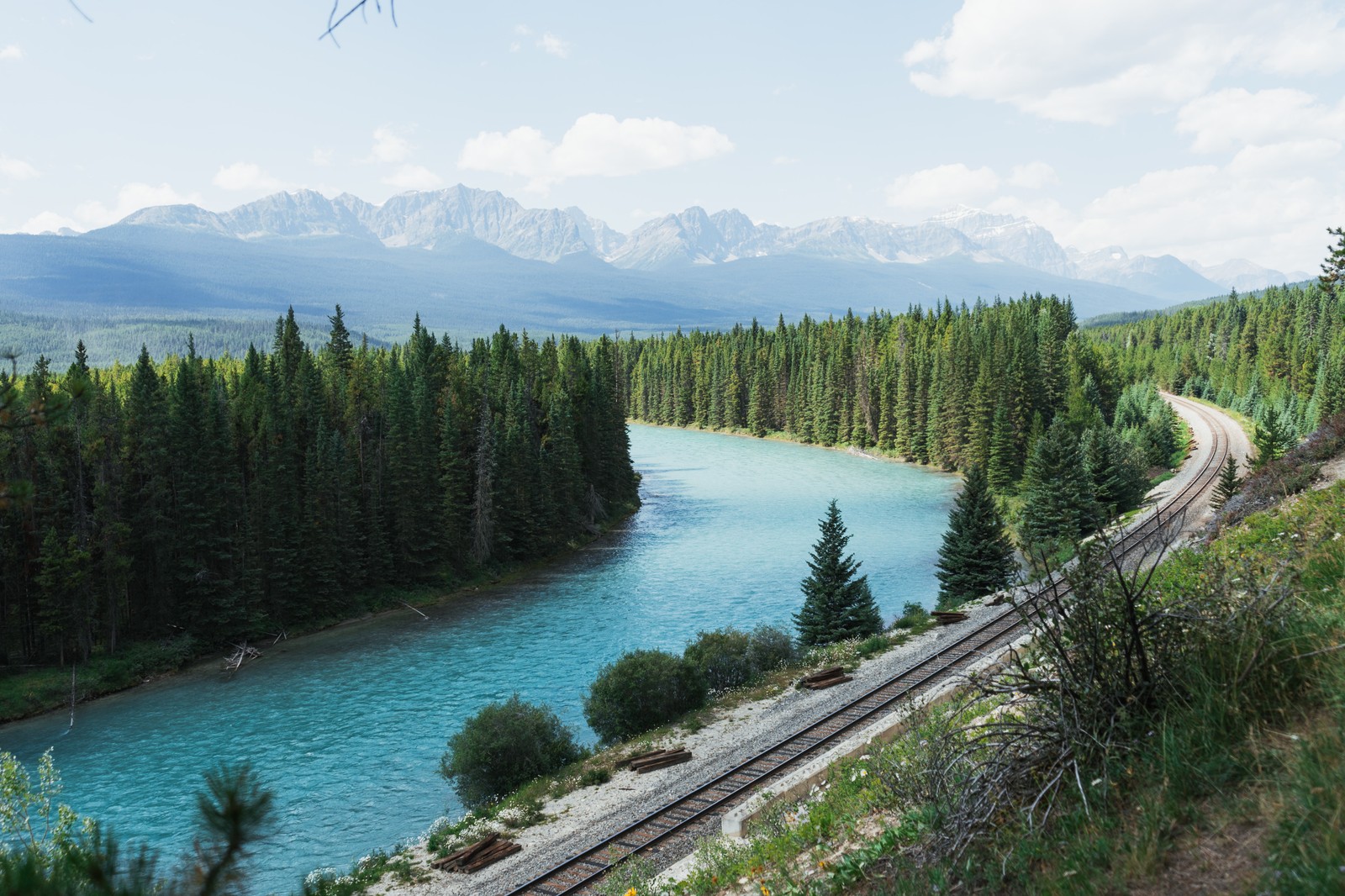 Trem árabe nos trilhos ao lado de um rio e montanhas (lake louise, água, nuvem, planta, recursos hídricos)