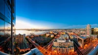 Paysage urbain vibrant au crépuscule, présentant un mélange de gratte-ciels modernes, de rues urbaines et de vues sur le front de mer dans une métropole animée.