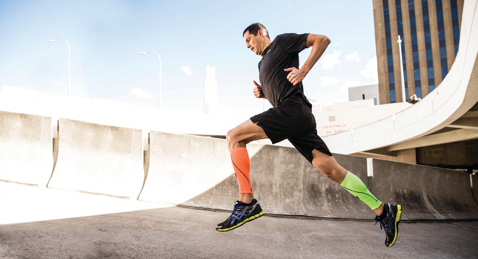 Un hombre en vista aérea corriendo en una calle de la ciudad con un puente de fondo (calcetín, ropa, deportes, correr, recreación)