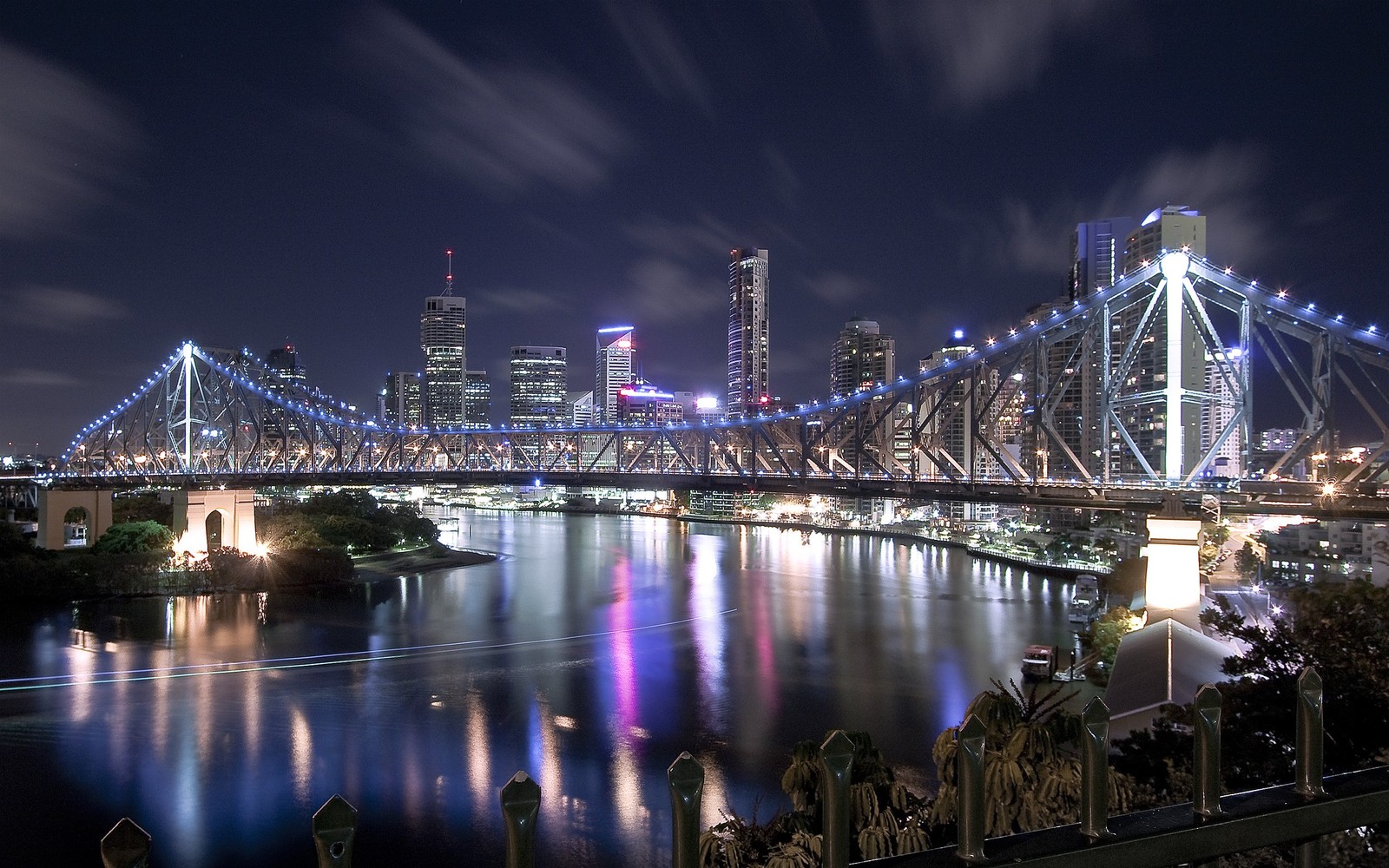 Visão aérea de uma cidade à noite com uma ponte e um rio (ponte, ponte arco íris, noite, paisagem urbana, reflexo)