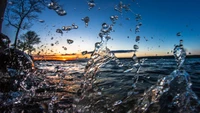 Salpicaduras de agua dinámicas contra un sereno atardecer sobre aguas azules