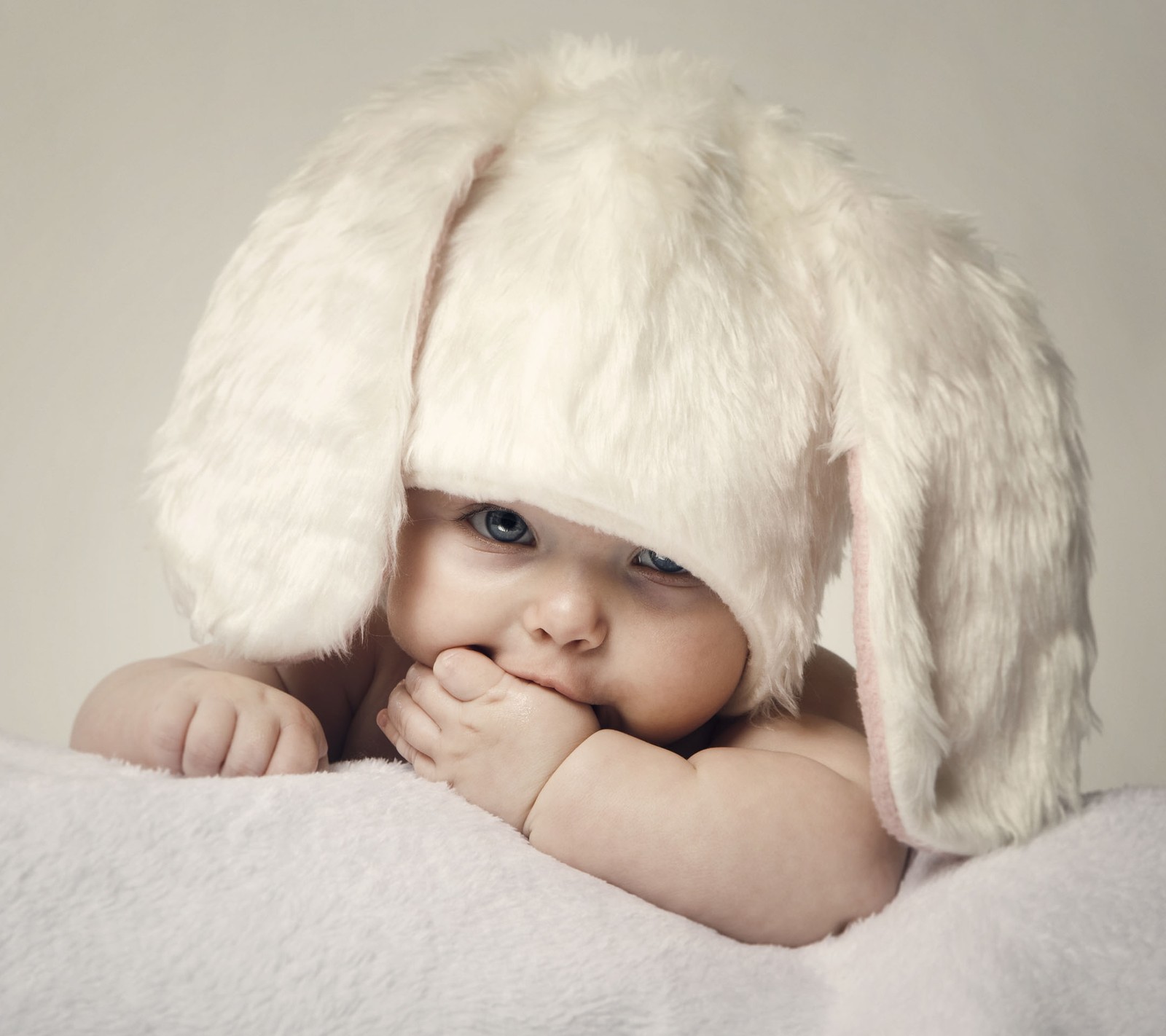 Ein baby mit einem hasenhut auf einer decke (baby, kinder, niedlich, hd, kind)