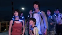 Characters from "Alice in Borderland" Season 2, standing together with glowing harnesses, in a tense and suspenseful moment under a night sky.