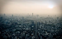 Une vue panoramique d'un horizon métropolitain animé au coucher du soleil, mettant en valeur des gratte-ciels et un vaste paysage urbain sous un ciel brumeux.