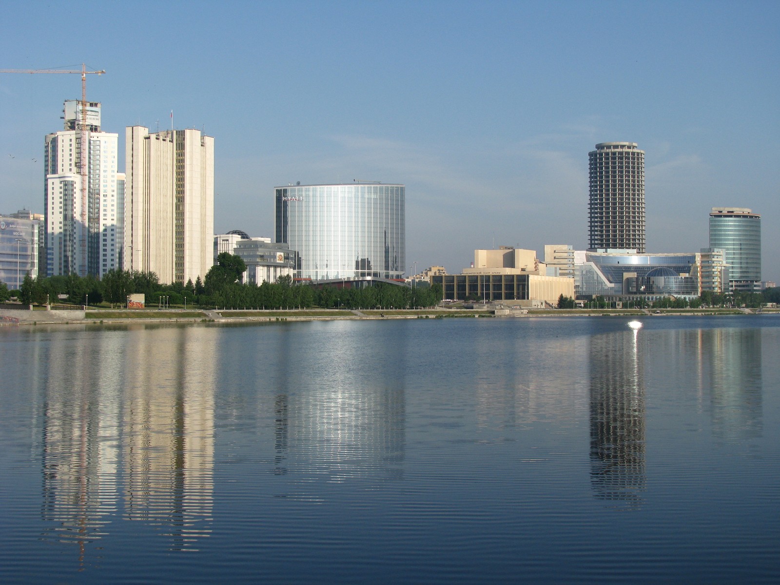 Una vista del horizonte de una ciudad con un lago y un bote (ekaterimburgo, ciudad, panorama, reflexión, día)