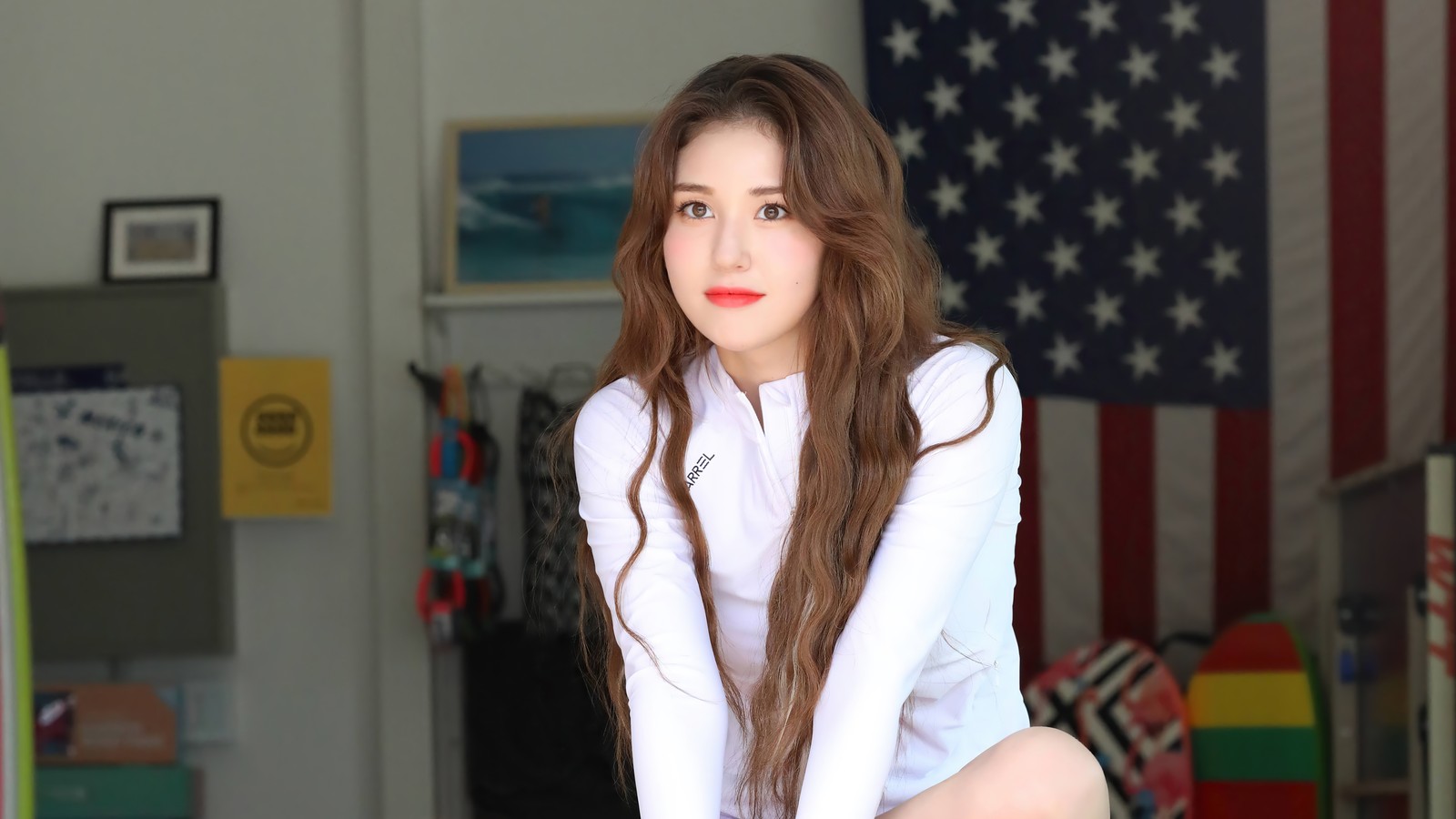 Una mujer sentada sobre una maleta en una habitación con una bandera americana (somi, 소미, ennik somi douma, jeon somi, jeon so mi)