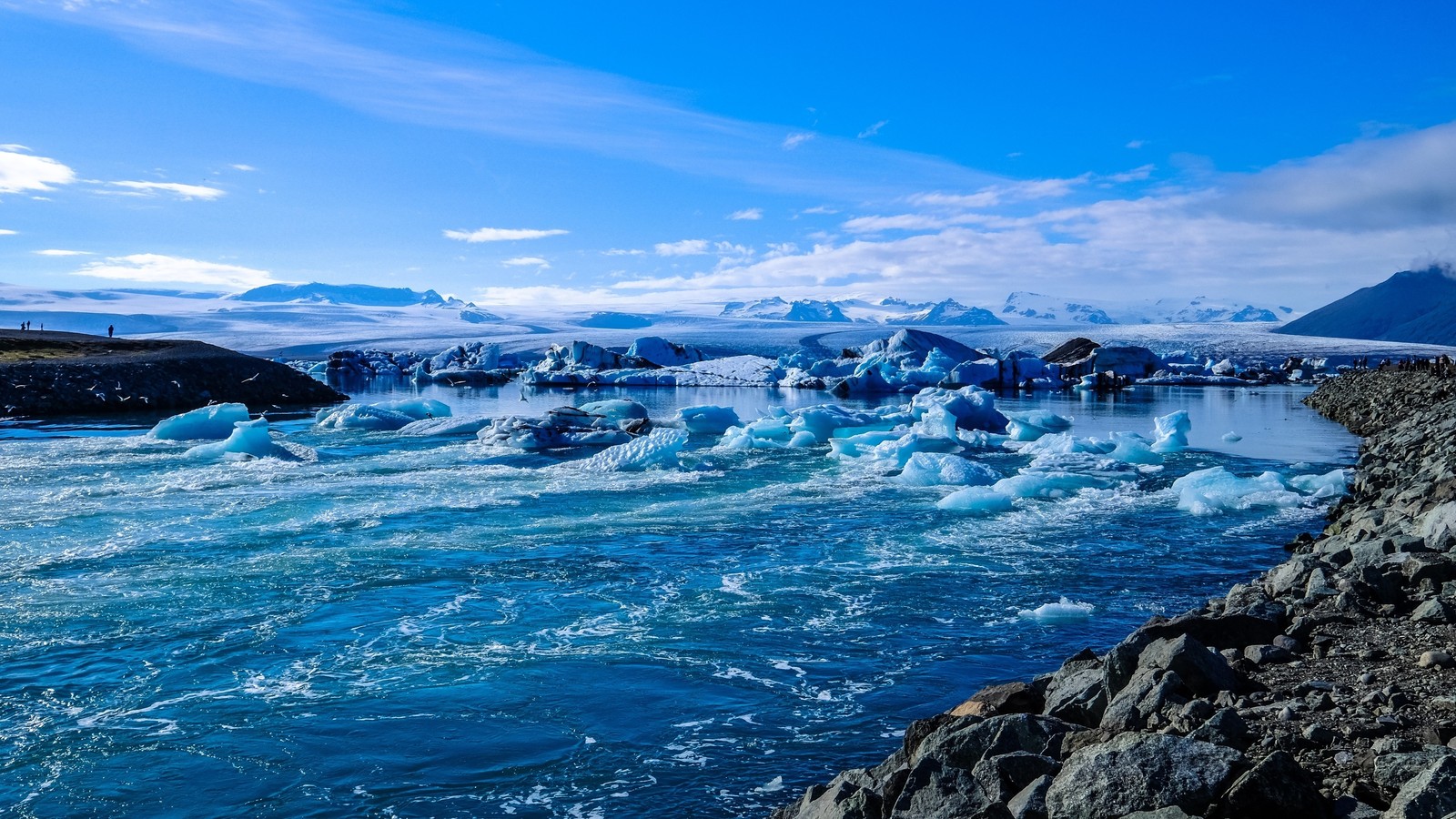 Um grupo de icebergs flutuando em um corpo de água. (oceano, mar, água, onda, lago glacial)