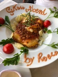 Vegetarian dish garnished with fresh herbs, cherry tomatoes, and a savory sauce, presented on elegant dishware.