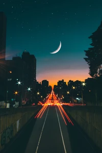 Paysage urbain au crépuscule : rues illuminées sous un croissant de lune