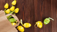 Yellow Tulips and Colorful Easter Eggs on a Wooden Surface