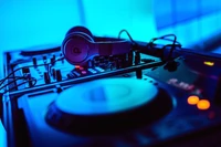 Beleuchteter DJ-Mixer mit Kopfhörern in einem lebhaften blauen Tonstudio-Setting