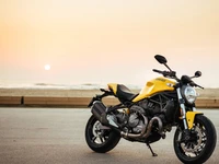 Ducati Monster: Une moto sportive jaune au lever du soleil près de la mer