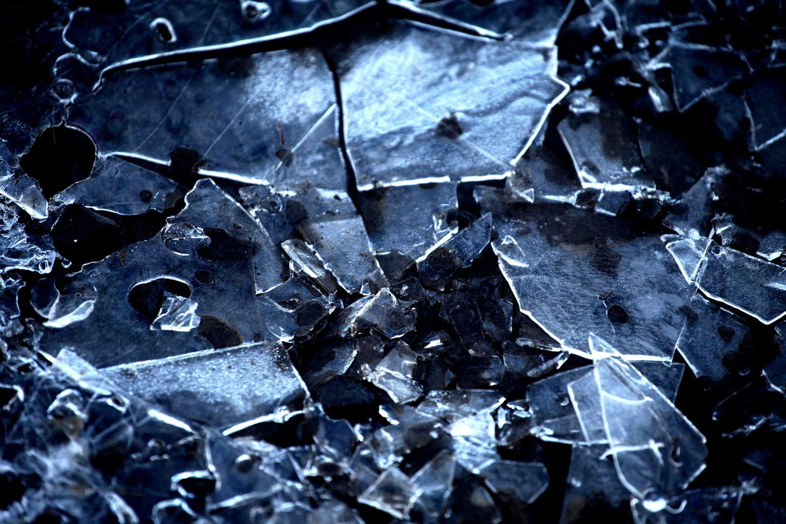 A close up of a broken glass with a black background (water, blue, ice, freezing, winter)